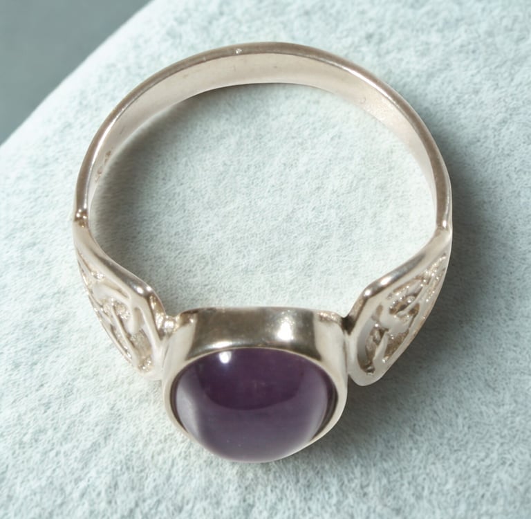 Handcrafted silver Celtic ring featuring a round purple amethyst cabochon gemstone.