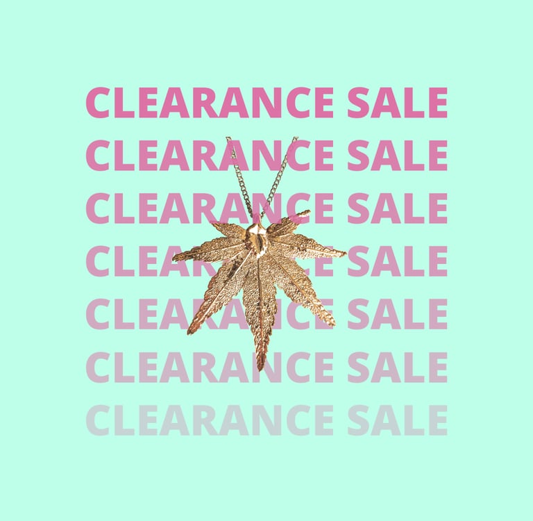 Gold maple leaf pendant necklace on a mint background with pink clearance sale text overlays.