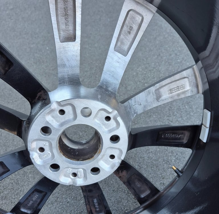 Inner view of a multi-spoke alloy car wheel rim showing the hub assembly and stamped serial numbers.