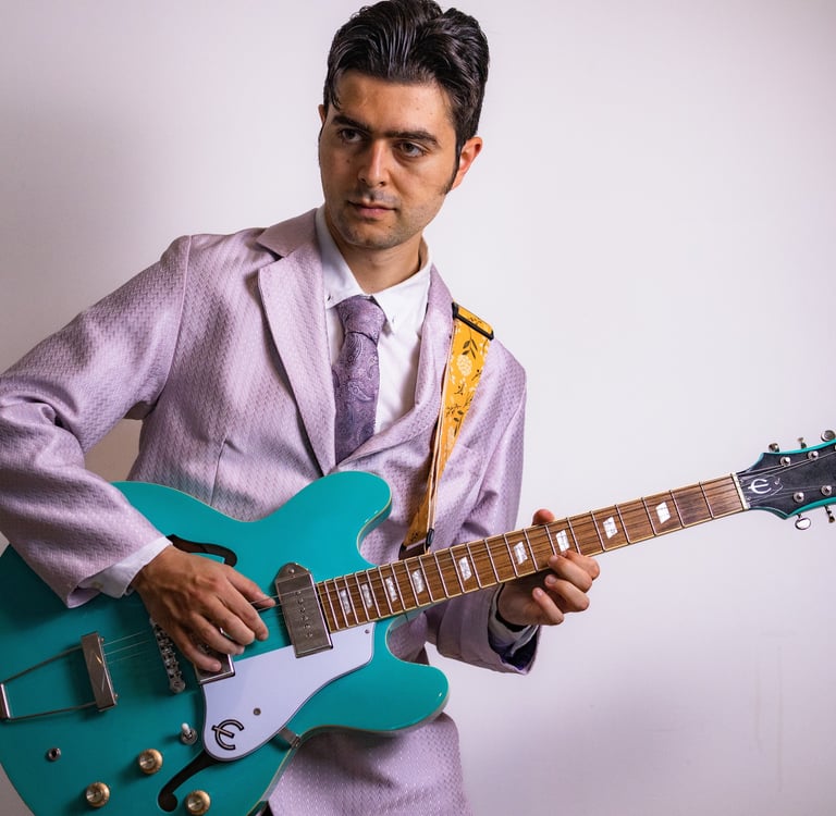 Olly Williams Brighton musician posing with turquoise electric guitar in studio