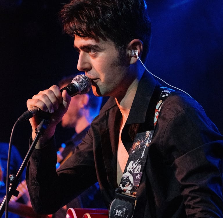 Live Brighton performance by rock and roll singer Olly Williams with his band, playing guitar on stage.