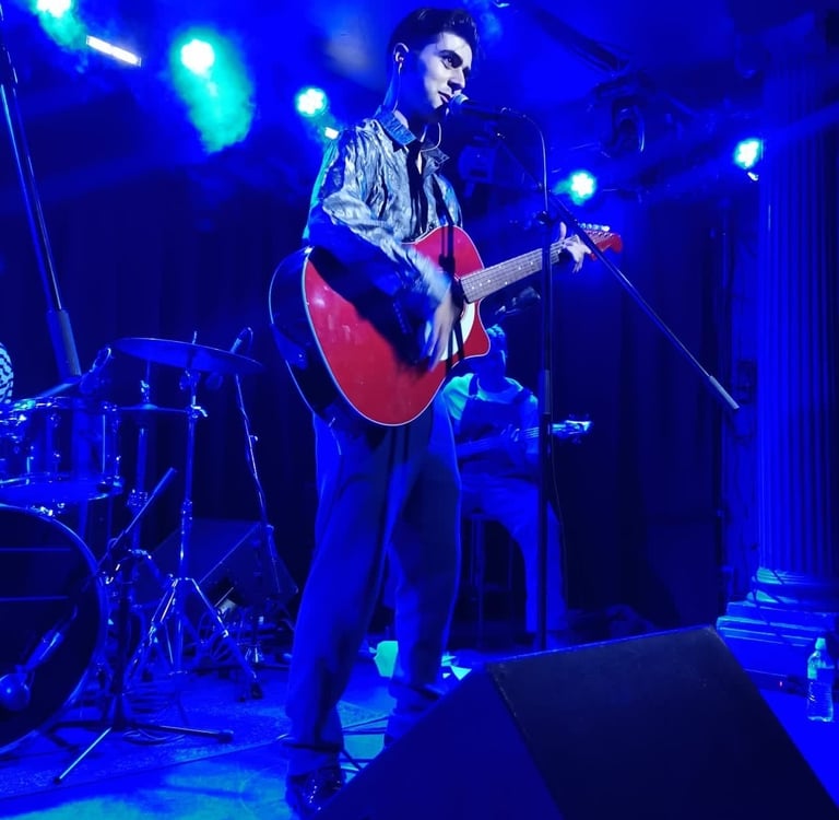 Olly Williams Brighton UK live musician performing with red guitar under stage lights