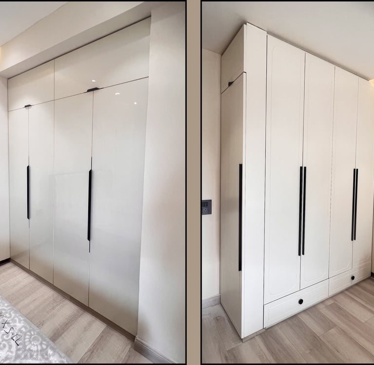 Modern custom white built-in floor-to-ceiling wardrobe with sleek black handles and wood flooring.