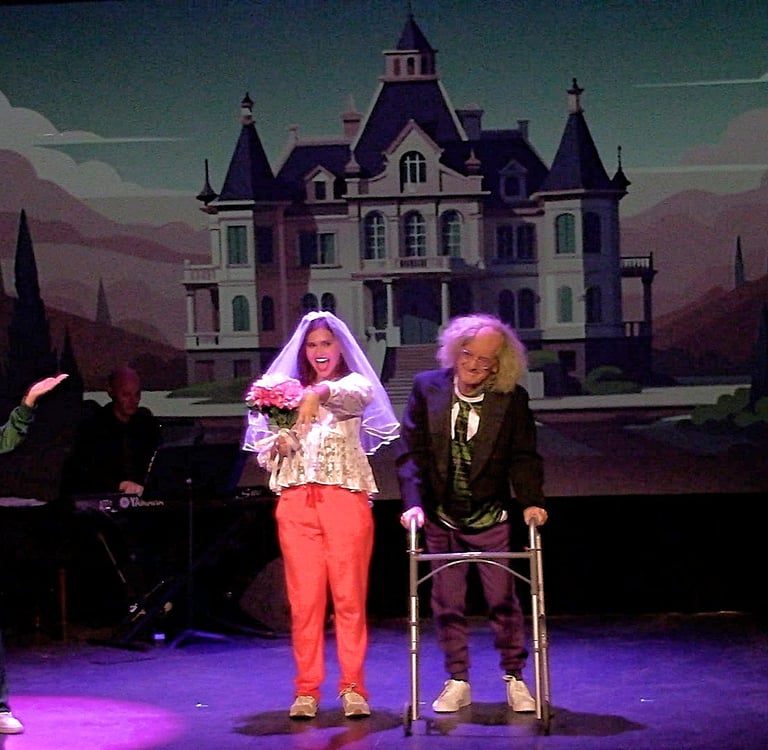 A theatrical comedy performance on stage featuring actors in costumes with a haunted mansion backdrop.