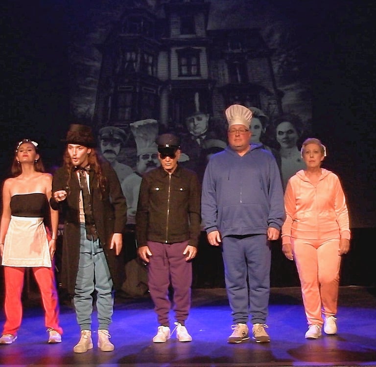 Actors in colorful costumes a musical number in front of a haunted house backdrop.