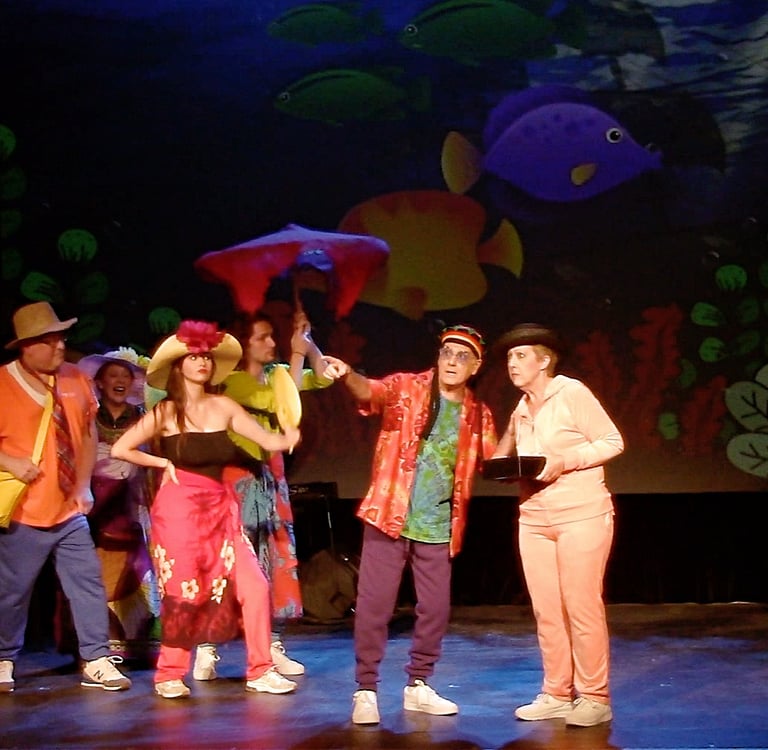 Actors in colorful costumes perform a comedy musical number with a tropical fish backdrop.