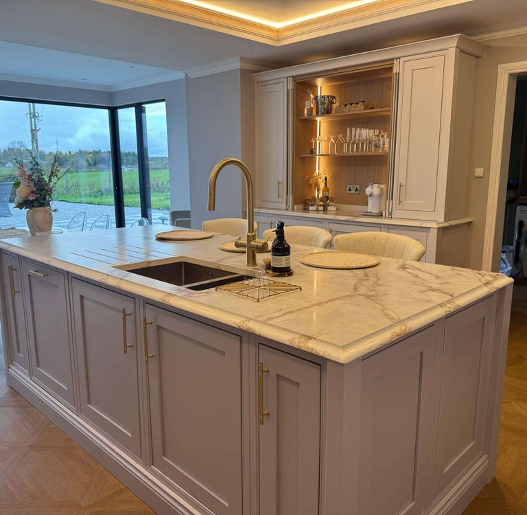 Luxury kitchen island with white marble countertop, gold faucet, and elegant grey cabinetry.