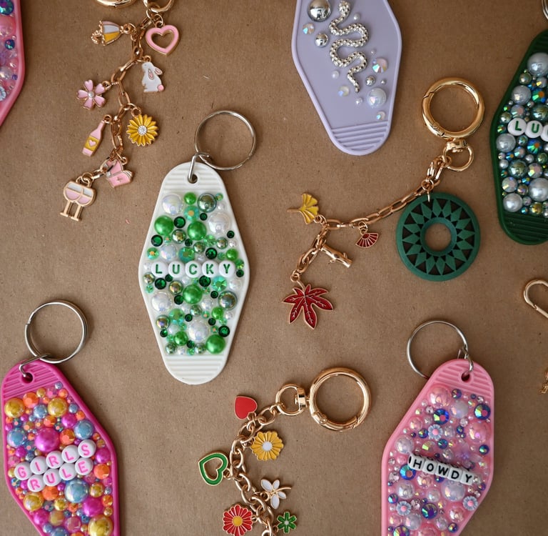 Collection of colorful beaded hotel key tag keychains with lucky and howdy charms on a brown surface.