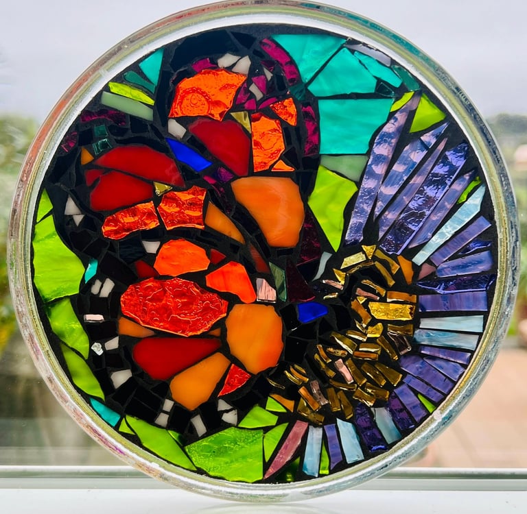 Vibrant, circular glass mosaic featuring a monarch crafted from hand cut tesserae.