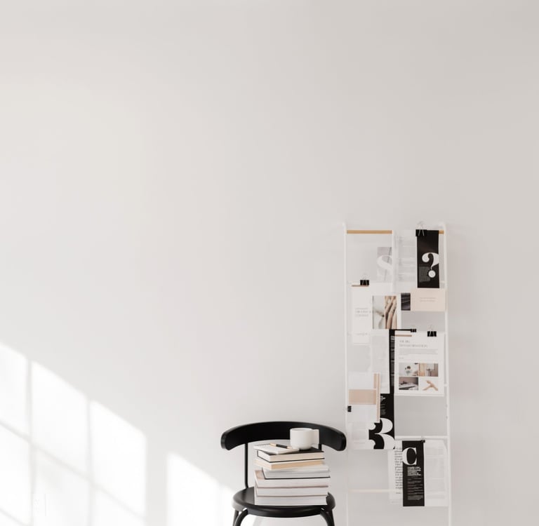 A black chair with a stack of books with a notepad and pen on top.