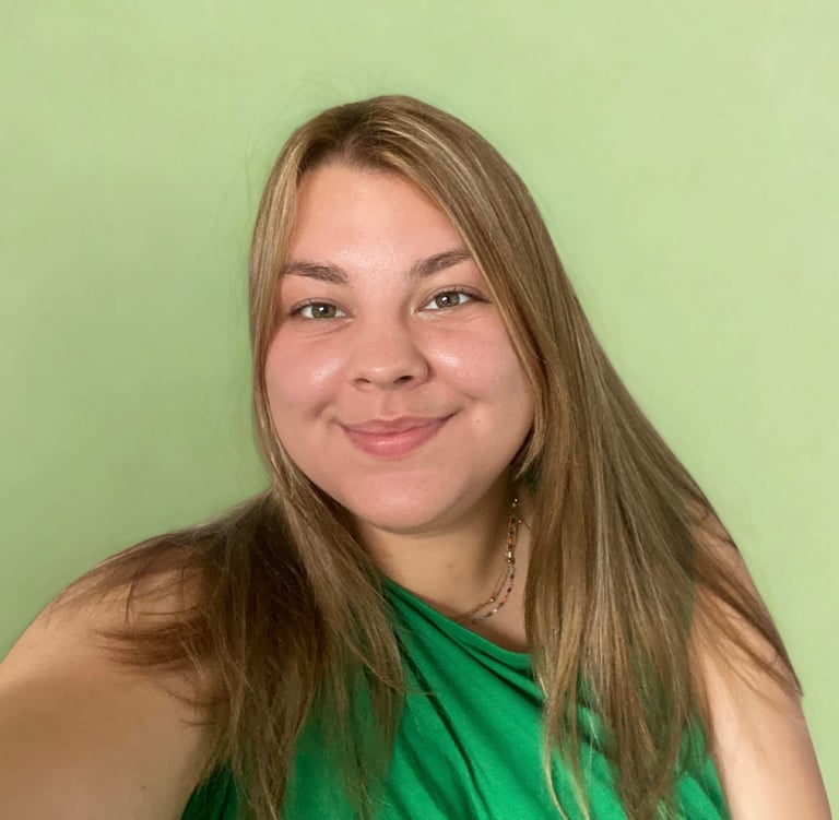 Glimlachende vrouw met lang bruin haar in groene top tegen zachte groene achtergrond.