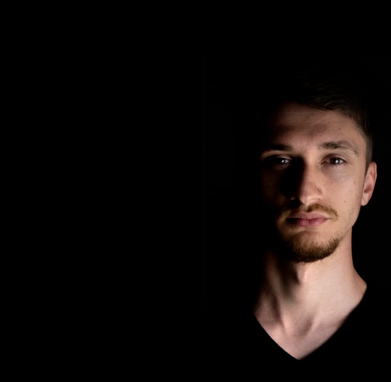 Close-up shot of music artist Valah's face in the dark, illuminated by dramatic lighting.