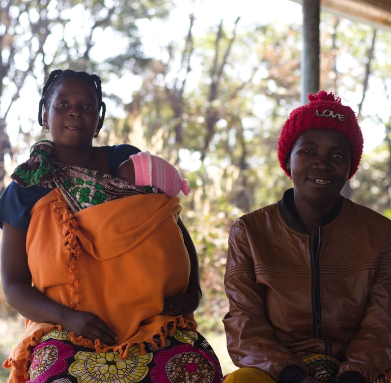 two women sitting on a bench in a outside a rural community centre in Ndola, Zambia