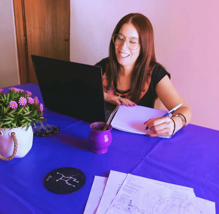 a woman sitting at a table with a laptop and a notebook