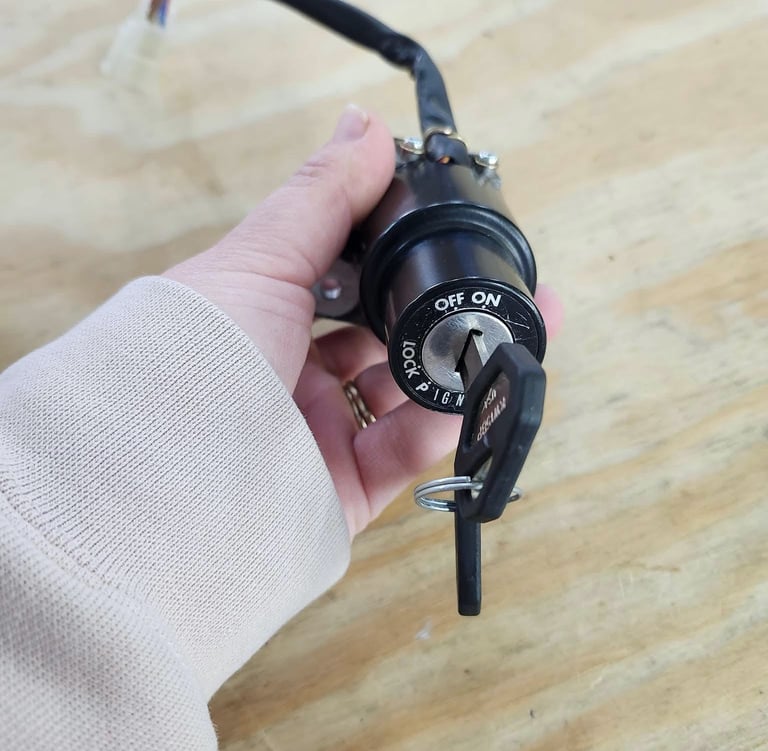 Hand holding a motorcycle ignition cylinder with key inserted