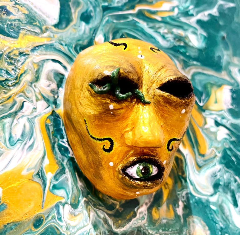 une sculpture sans yeux avec un oeil dans la bouche qui émerge d'une toile verte vu de près