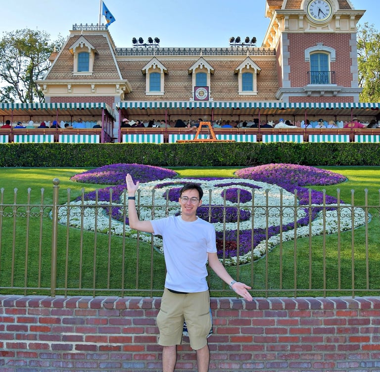Travel Agent Andrew stands in front of the Main Street Train Station at the entrance to Disneyland.