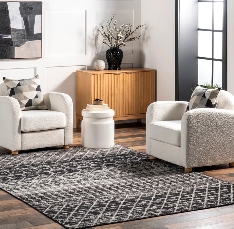 Modern living room with black and gray geometric area rug, white bouclé armchairs, and wooden sideboard.