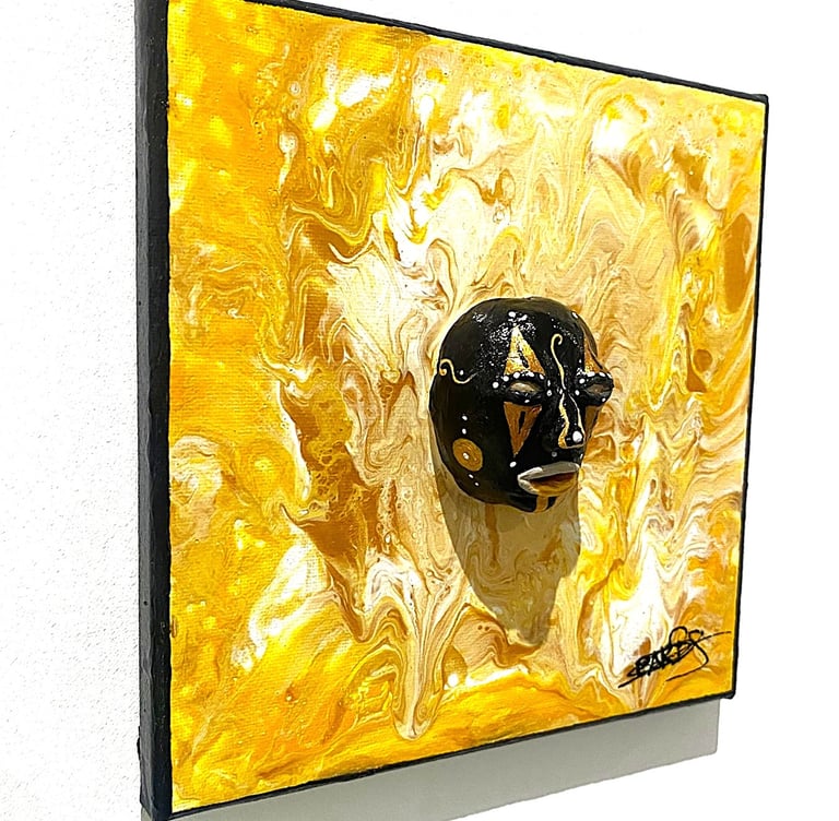 uns sculpture noir ressemblant à un masque qui émerge d'un tableau jaune vu de côtés