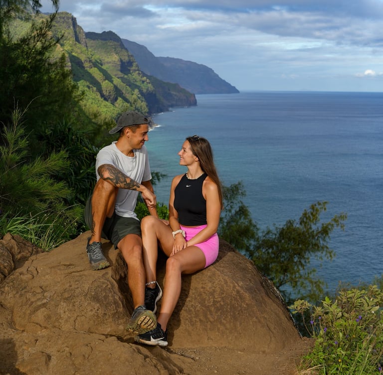 a man and woman sitting on a rock in hawaii