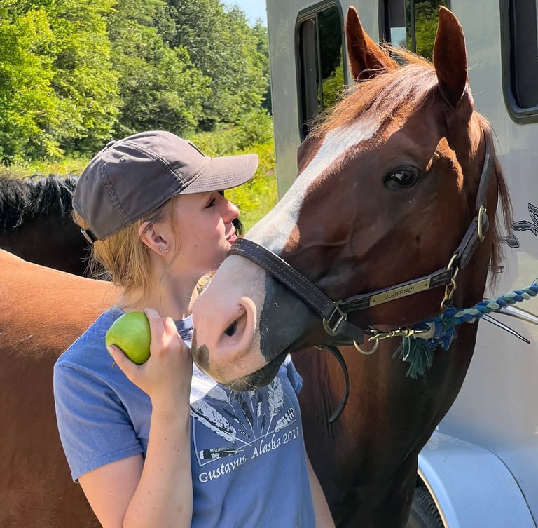 a woman in a hat and a horse at a trailer