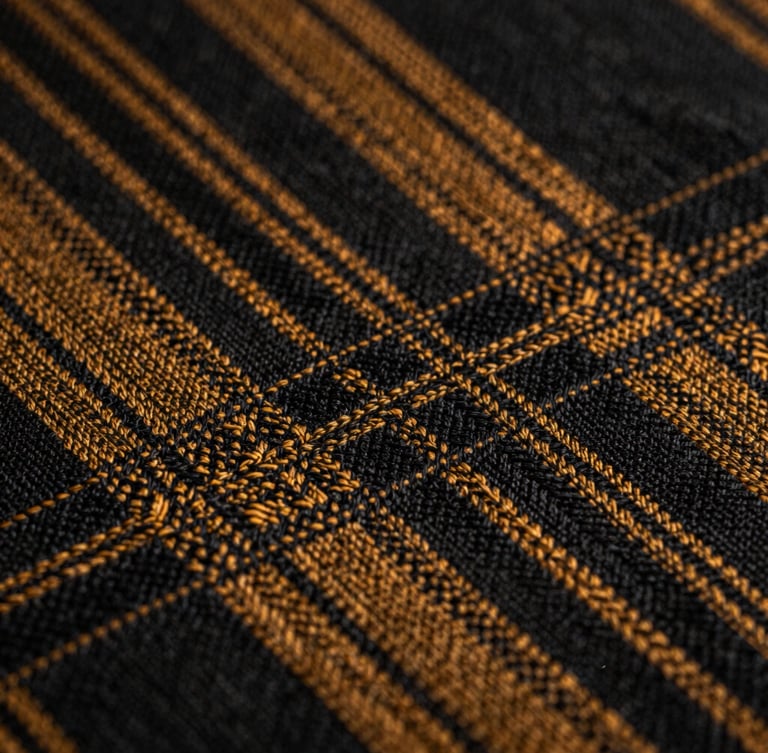Extreme close-up macro shot of authentic Alindi cloth showing sharp geometric weaving patterns of black and deep amber threads under high-contrast chiaroscuro lighting.