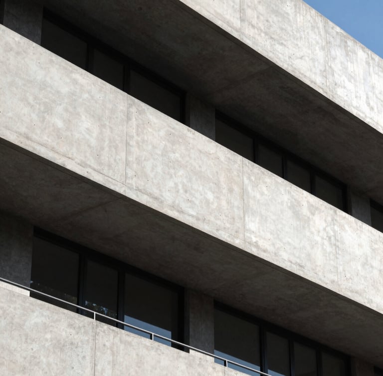 High-contrast architectural crop of a modern concrete and steel facade, sharp geometric shadows under bright daylight, clean lines, minimalist composition.