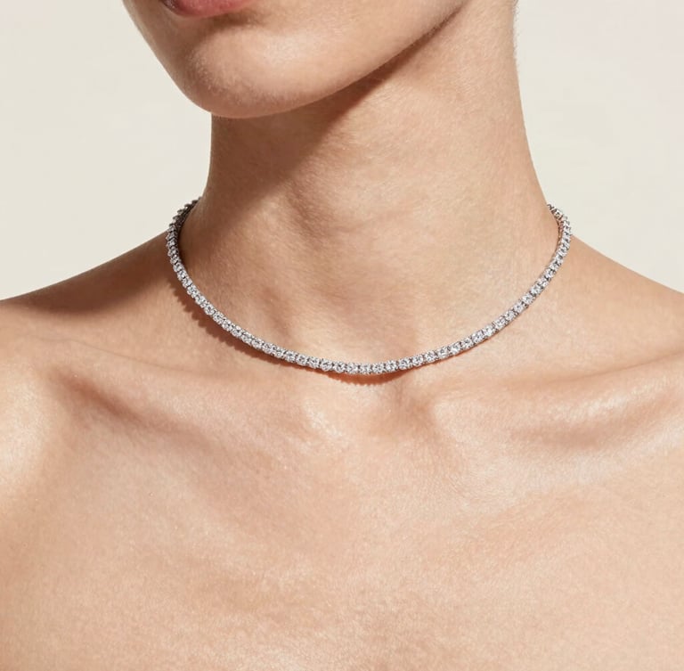 Elegant close-up of a model's collarbone wearing a delicate diamond necklace, soft diffused daylight, clean hydrated skin, high-fashion editorial, 35mm
