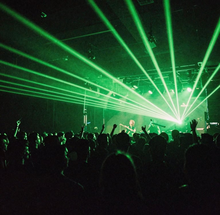 Wide-angle gritty concert crowd shot from behind the stage, intense neon green laser beams cutting through deep shadows, heavy 35mm film grain, electric atmosphere.