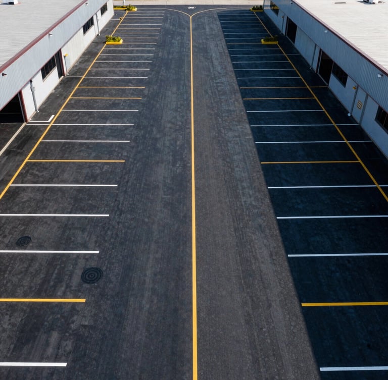 Symmetrical overhead drone shot of a freshly striped multi-acre commercial logistics center parking lot with perfect yellow and white lines, high contrast.