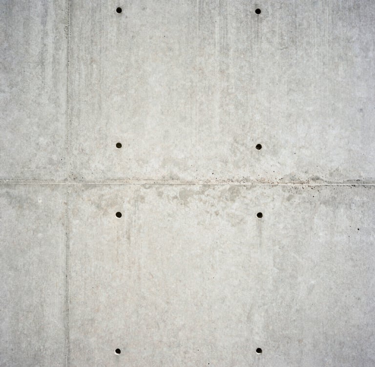 Close-up of a freshly poured concrete wall, high-contrast, harsh direct sunlight, sharp focus, architectural film photography, 35mm lens.