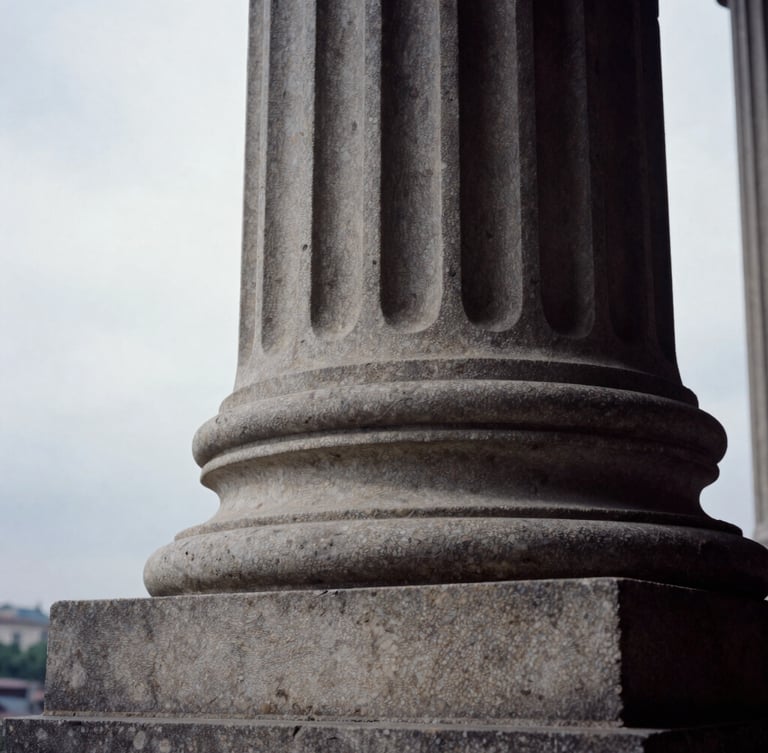 Extreme close-up of a carved stone classical pillar, deep shadows, natural overcast side-lighting, editorial architectural photography, 35mm film