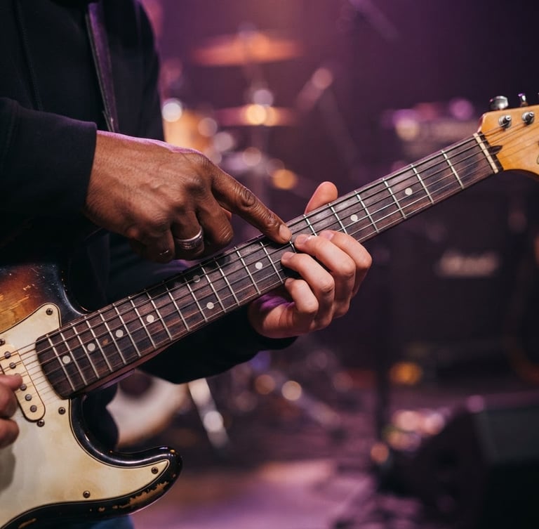 A close-up of a student's hands learning electric guitar frets from an instructor, warm purple stage backlighting, premium editorial photography style.