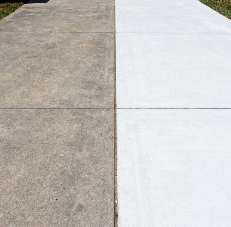 A sharp split-screen before-and-after shot of a concrete driveway, one side dark with years of dirt, the other side brilliant clean white concrete under bright direct sunlight, 35mm lens.