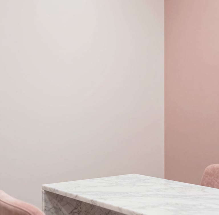 Minimalist interior corner of a luxurious nail salon in Antwerp, soft warm-white walls, dusty rose accents, clean marble table, serene atmosphere