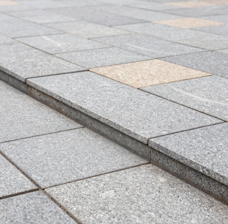 A close-up architectural shot of perfectly aligned gray stone pavers, showing crisp geometric joints and a level edge, bright overcast daylight, rich textures of premium materials.