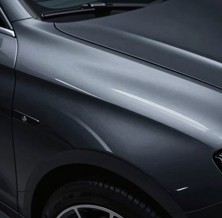 Sleek automotive photography of a high-gloss black fender panel, cool studio LED lighting reflecting a sharp white line, close-up macro lens.
