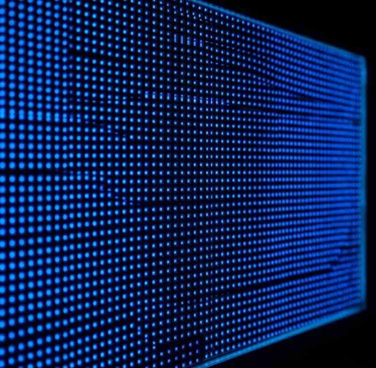 Close-up of a commercial LED display panel showing vibrant electric blue pixels, set against a dark background with a subtle edge-light, sharp focus on the panel's surface, wide aspect ratio
