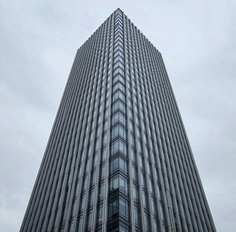 Symmetrical wide-angle architectural shot of a modern corporate skyscraper exterior, steel and glass facade, cool overcast daylight, sharp clean lines, negative space on the left.