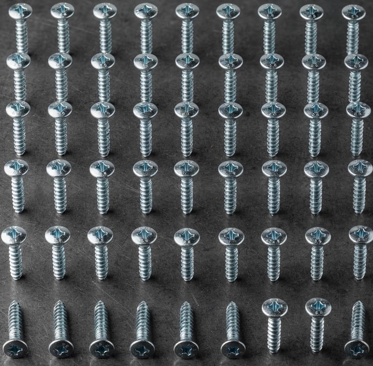 Macro shot of organized zinc-plated steel screws on a clean dark gray metal background, crisp studio light, industrial precision framing