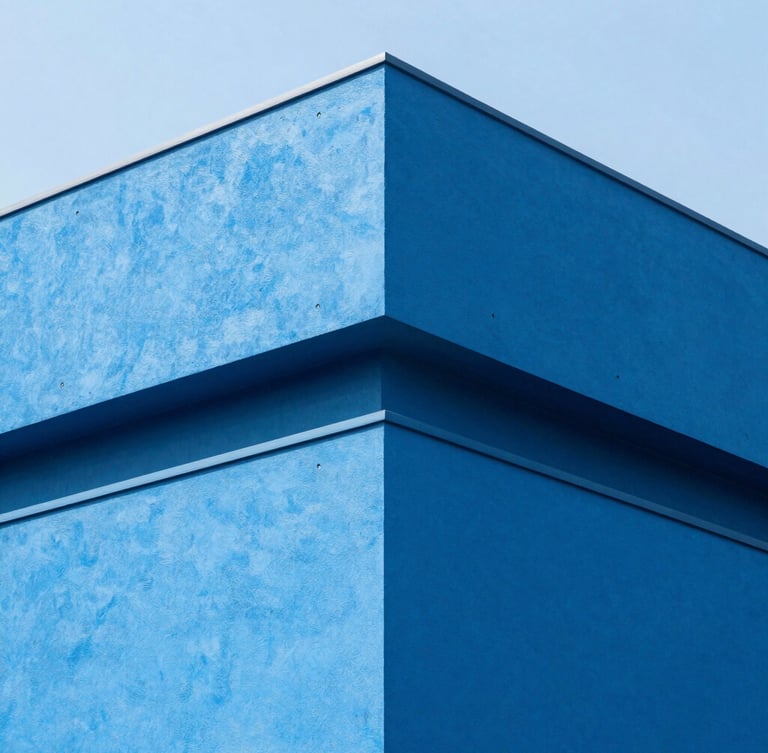 Sharp architectural corner of a modern concrete building painted in clean electric blue, high-key natural daylight, deep shadows, 35mm lens