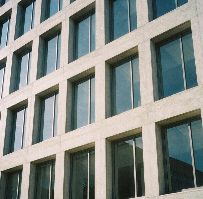 An architectural close-up of a modern concrete and glass building facade in Salt Lake City, soft morning daylight, cool shadows, minimalist composition.