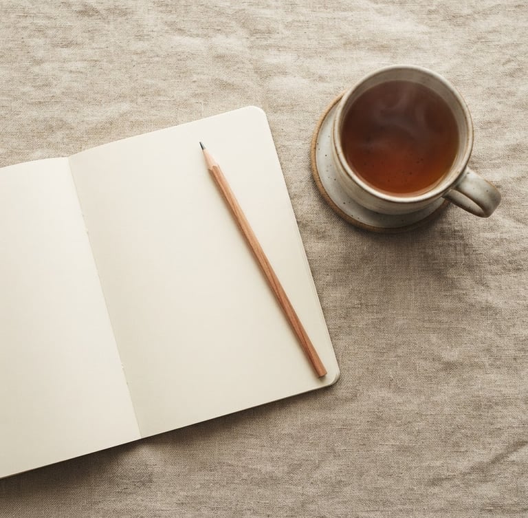 An overhead flat-lay of a minimalist notebook, a wooden pencil, and a warm cup of tea on a textured linen surface, soft morning daylight, shallow depth of field.
