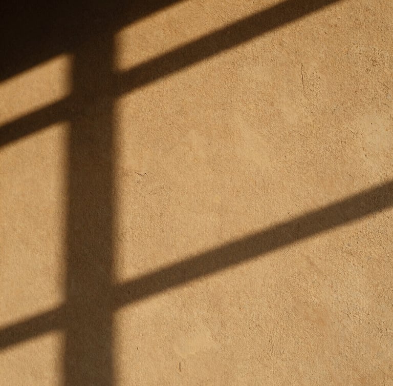 Warm raw plaster wall catching low-angle afternoon sunlight, soft long shadows, tactile texture, minimal composition, 35mm photography