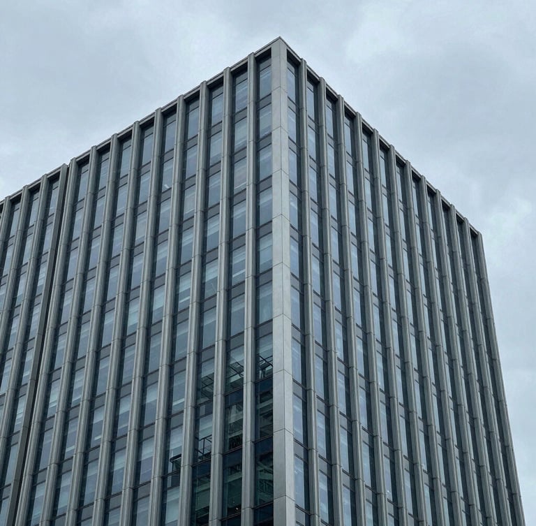 Architectural portrait crop of a modern corporate skyscraper corner, clean steel lines against an overcast gray sky, cool tones, 35mm