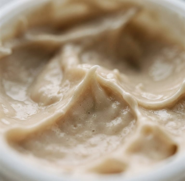 Macro shot of rich cosmetic cream texture, soft natural window light, muted sand and cream tones, shallow depth of field, 35mm