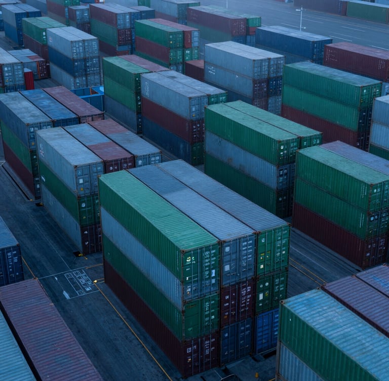 High-altitude drone photograph of a geometric container terminal at twilight, cool blue tones, perfectly aligned stacks of green and grey shipping containers, misty atmosphere.
