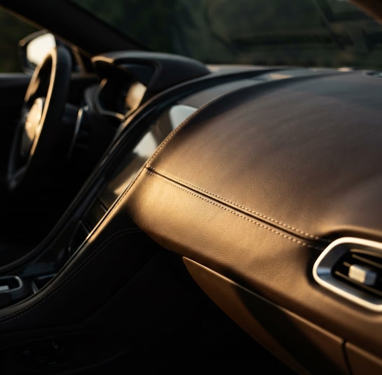 Extreme close-up of a luxury vehicle's leather interior, focusing on sleek dashboard lines and premium stitching, low-key dramatic lighting, wide-angle lens, high-contrast rich tones.