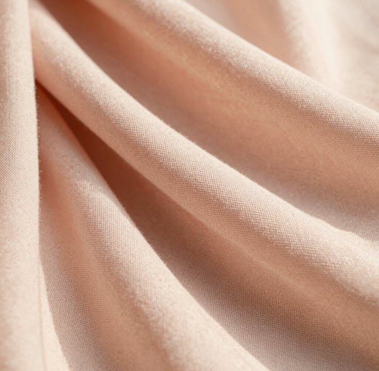 Macro close-up of a soft blush pink georgette scarf showing delicate woven fabric texture, warm diffused golden hour light, soft shadows, premium editorial photography