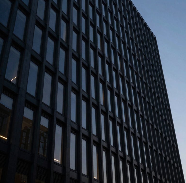 Imposing modern corporate building facade at dusk, sharp architectural lines, dramatic low-key lighting, reflecting deep navy and charcoal tones, viewed from a low angle, cinematic, 35mm.